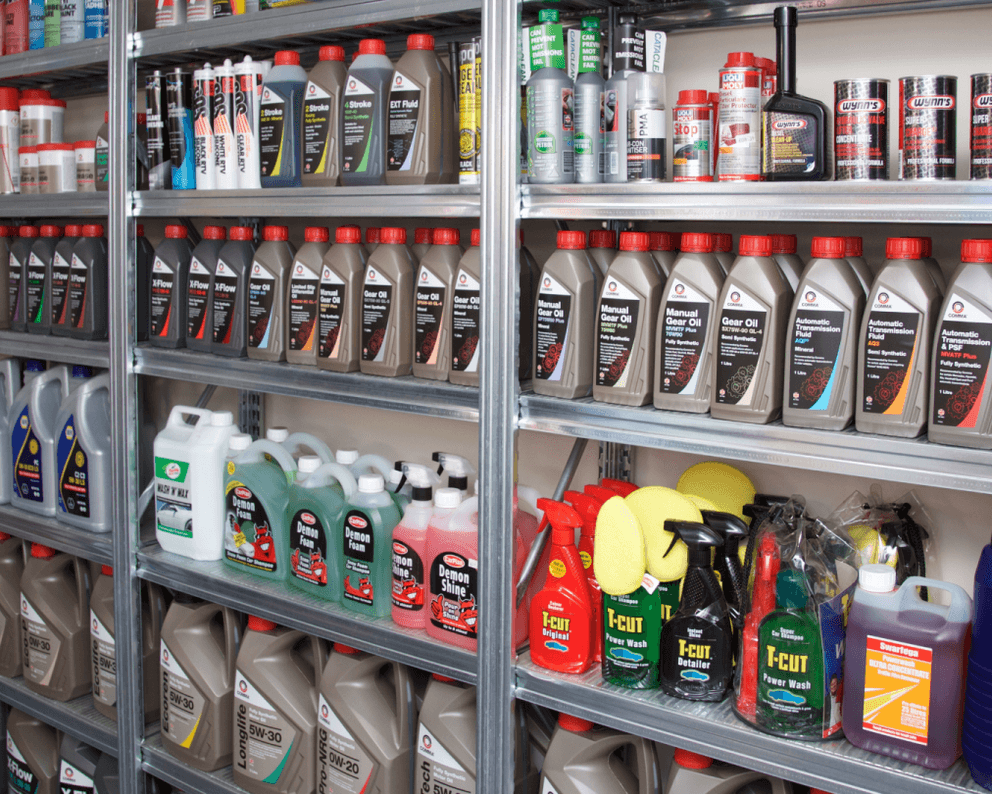 Metal shefing with a variety of car related liquid bottles on such as motor oil and car wash foam